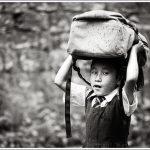 A little girl hold her school bag above her head during rains