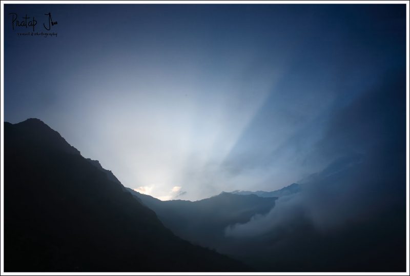 The sun rises from behind the mountains in the Himalayas on the Kuari Pass trek