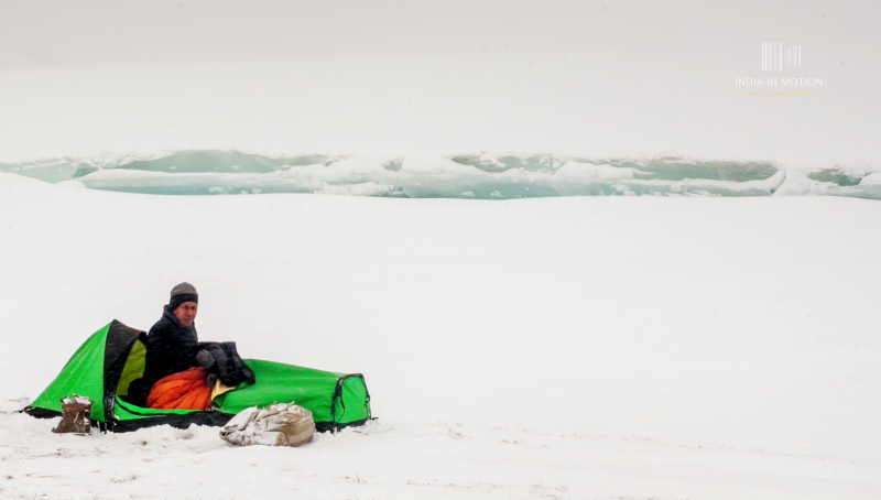 A man inside a green tent during a snow storm in Ladakh