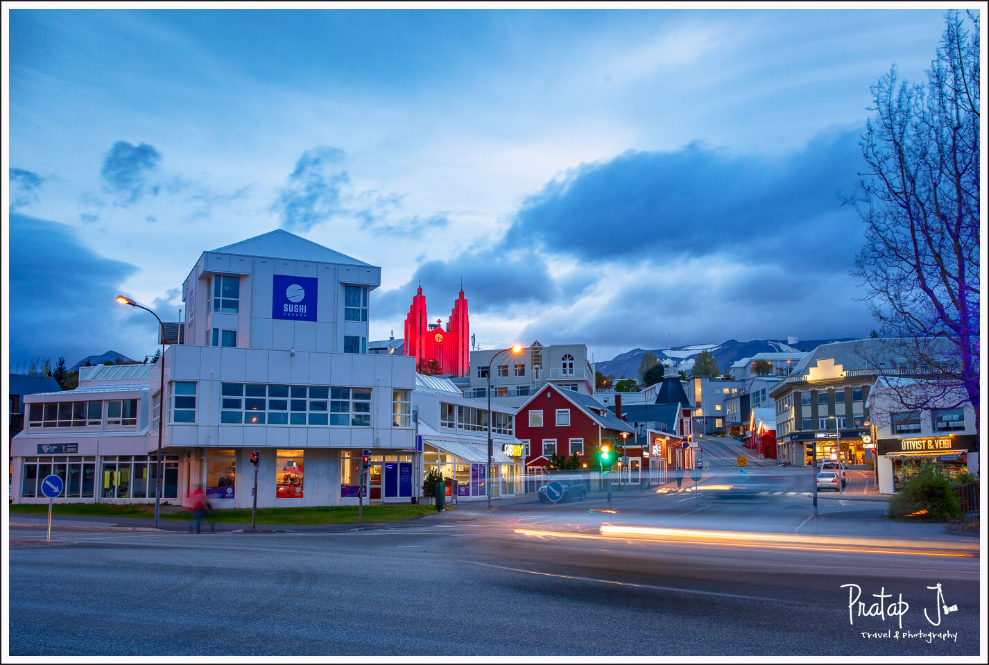 A traffic junction of Akureyri with colours buildings and he mountain the background
